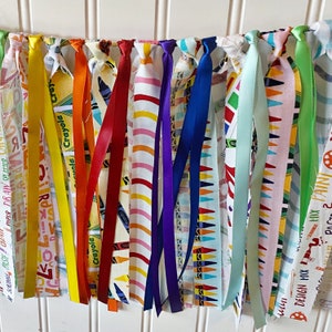 May include: A colorful fabric banner with various patterns and colors, including red, yellow, blue, green, and white. The banner has the words "Crayola" and "Design Mix" printed on it.