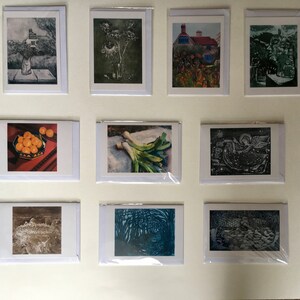 May include: A collection of 10 greeting cards featuring various images, including a house, a vase of flowers, a bowl of oranges, a bunch of leeks, a bird, a wave, a forest, and a stone wall.
