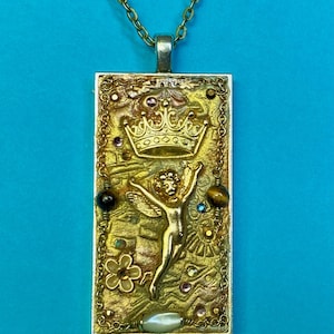 K&ouml;nnte beinhalten: Goldfarbene Anh&auml;nger Halskette mit einem rechteckigen Anh&auml;nger mit Krone, Engel und verschiedenen Edelsteinen. Der Anh&auml;nger hat eine strukturierte Oberfl&auml;che und h&auml;ngt an einer filigranen Kette. Der Hintergrund ist blau.