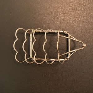 May include: Silver-plated, heart-shaped, wire toast rack. The rack is designed to hold four slices of toast.