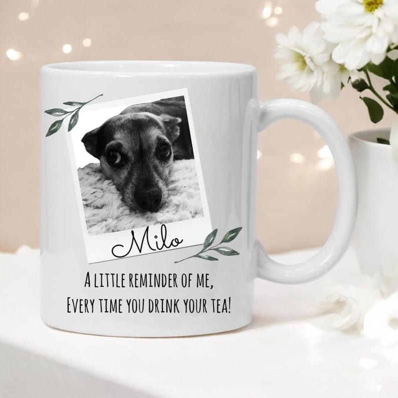 Peut inclure: Une tasse en c&eacute;ramique blanche avec une photo en noir et blanc d'un chien dans un cadre Polaroid. Le texte "Milo" est &eacute;crit sous la photo. La tasse a &eacute;galement des feuilles vertes et le texte "Un petit rappel de moi, &agrave; chaque fois que vous buvez votre th&eacute; !"