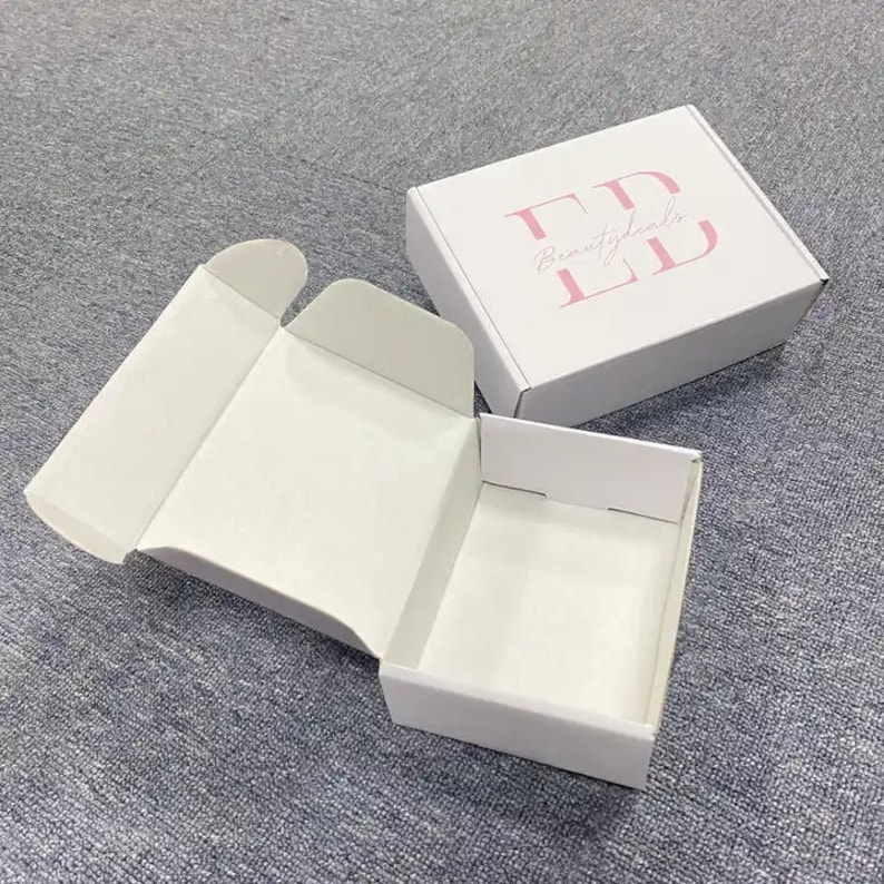 May include: White cardboard box with a pink logo that says "Beauty Deals" on the top. The box is open and the inside is empty.
