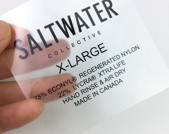 May include: A clear clothing label with black text that reads "SALTWATER COLLECTIVE X-LARGE 78% ECONYL® REGENERATED NYLON 22% LYCRA® XTRA LIFE HAND RINSE & AIR DRY MADE IN CANADA"