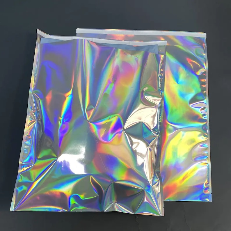 Puede incluir: Dos bolsas de env&iacute;o de pl&aacute;stico hologr&aacute;ficas iridiscentes. Las bolsas est&aacute;n selladas en tres lados y tienen una tira adhesiva transparente para sellar el cuarto lado.