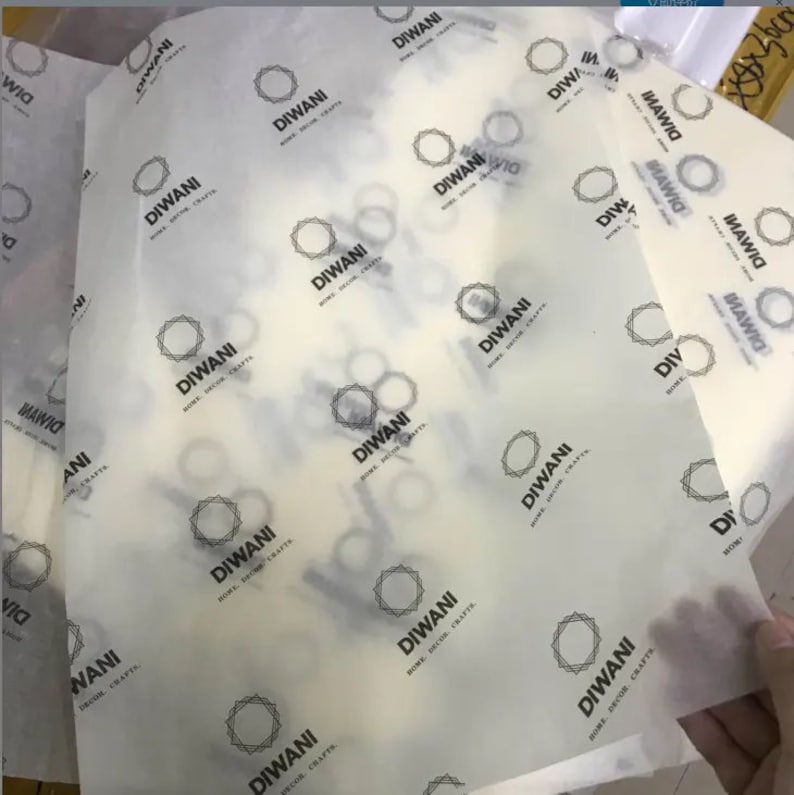 K&ouml;nnte beinhalten: Bl&auml;tter aus durchscheinendem wei&szlig;em Seidenpapier, bedruckt mit den Worten "DIWANI HOME DECOR CRAFTS" in Schwarz. Das Design beinhaltet ein geometrisches Sternmuster. Das Papier ist gefaltet und gestapelt.