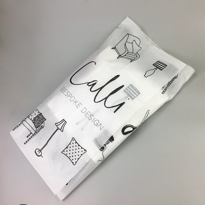 K&ouml;nnte beinhalten: Wei&szlig;es Seidenpapier mit schwarzen Strichzeichnungen von M&ouml;beln und den Worten "Calli BESPOKE DESIGN". Die Verpackung ist gefaltet und scheint einen Artikel zu enthalten.