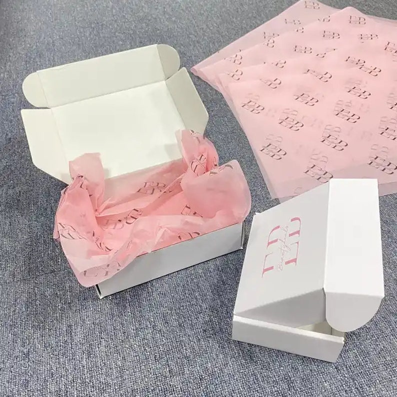 May include: Two white cardboard boxes with lids. One box is open and filled with pink tissue paper. The other box has the text "LD" printed on the side.