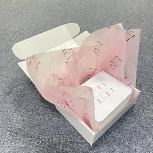 May include: A white box with a pink tissue paper lining. The tissue paper has a repeating pattern of the letters "LL" in a black font. The box is open and a smaller white box is inside. The smaller box has the text "Beauty Blvd" and the letters "LL" in a black font.