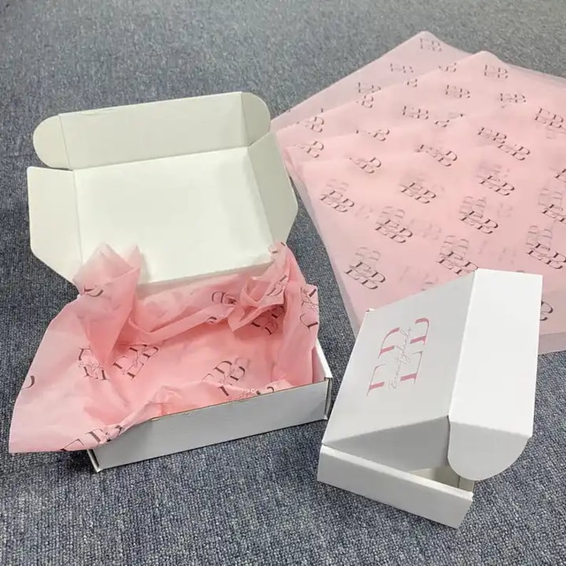May include: Two white cardboard boxes with pink tissue paper inside. The smaller box has the text "BB Beauty Boutique" printed on the side.