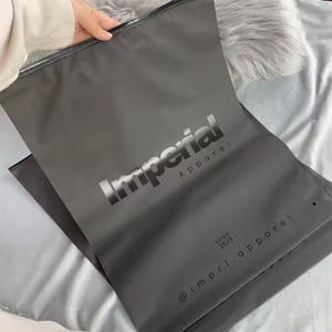 100 UVロゴカスタムジッパーTシャツバッグ、ロゴ付きUVプリント、リサイクル可能なプラスチックプライムブランドパッキング、つや消しブラックジッパー、衣類バッグ