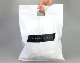Schwarze Einkaufstaschen mit Logo, individuell gestaltbar, aus Kunststoff mit Henkeln, ideal zum Einkaufen, für Gastgeschenke, Geburtstage, Partys und als Tragetasche mit Logo.