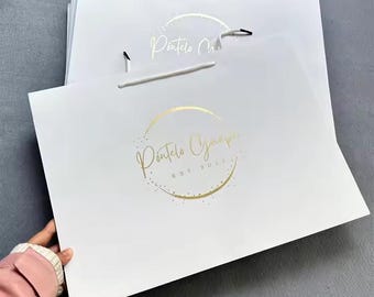 May include: White paper shopping bags with gold foil logos and white rope handles. The logo reads "Pontelo Group" inside a gold circle, with "EST 2022" below. The bags are stacked, with one held by a person.