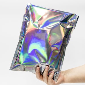Puede incluir: Una bolsa de pl&aacute;stico plateada iridiscente con una abertura termosellada. La bolsa est&aacute; arrugada y tiene un brillo arco&iacute;ris.