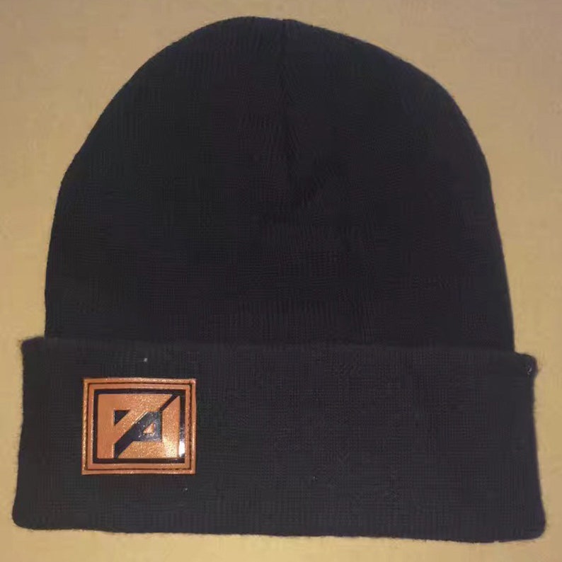 May include: Black beanie with a brown leather patch featuring a stylized "PA" logo.