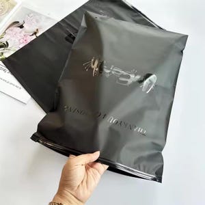 100 UVロゴカスタムジッパーTシャツバッグ、ロゴ付きUVプリント、リサイクル可能なプラスチックプライムブランドパッキング、つや消しブラックジッパー、衣類バッグ