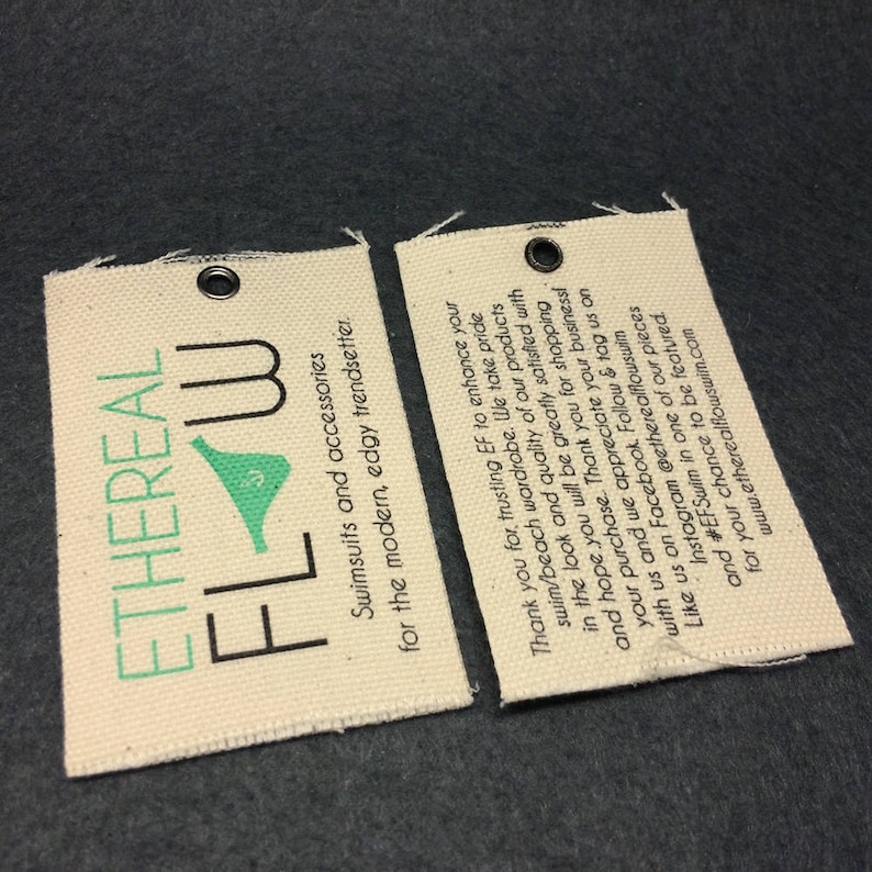 May include: Two white fabric tags with black text and a green logo. The text on the tags reads "Ethereal Flow Swimsuits and accessories for the modern, edgy trendsetter." and "Thank you for trusting EF to enhance your swim/beach wardrobe. We take pride in the look and quality of our products and hope you will be greatly satisfied with your purchase. Thank you for shopping with us and we appreciate your business! Like us on Facebook. Follow & tag us on Instagram @etherealflowswin and #EFSwim in one of our pieces for your chance to be featured. www.etherealflowswim.com"