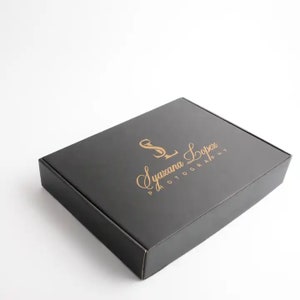 May include: Black cardboard box with a gold logo that says "Syazana Lopez Photography" in a cursive font.