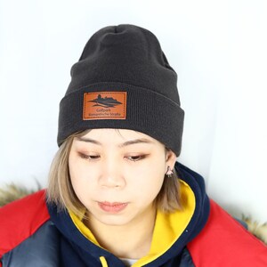 May include: A black knit beanie with a brown leather patch that says "Golfpark Romantische Stra&szlig;e".