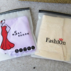 Pu&ograve; includere: Due sacchetti di plastica trasparente con cerniera e cerniere nere. Un sacchetto contiene un tessuto viola con una figura femminile rossa che indossa un vestito rosso e il testo "S 女人  秀出好身材". L'altro sacchetto contiene un tessuto beige con il testo "Fashion" e una corona.