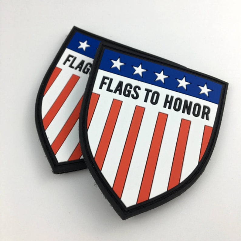 May include: Two red, white, and blue embroidered patches with a shield shape. The patches have a black border and the text "FLAGS TO HONOR" in black lettering.