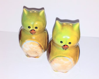 May include: A set of two ceramic owl salt and pepper shakers. The owls are green with brown accents and have black eyes and orange beaks.