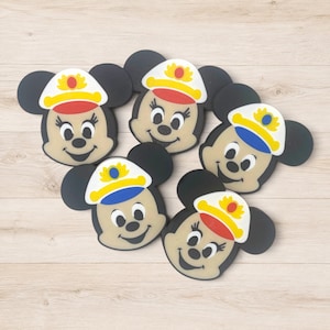 Puede incluir: Cinco iconos de personajes circulares y planos con orejas de ratón negras y caras de color tostado. Cada personaje lleva una gorra de capitán en blanco, amarillo y rojo o azul. Las caras tienen ojos, narices y sonrisas negras.