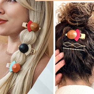 Puede incluir: Un conjunto de cuatro pinzas para el pelo con formas geométricas y detalles de madera. Las pinzas son de color marrón, rojo, negro y turquesa. El texto "ECO HAIR accessories" es visible en la imagen.