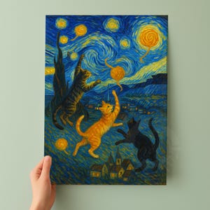 Op de afbeelding: Een canvas print met een grillige sc&egrave;ne ge&iuml;nspireerd op Van Goghs "Starry Night". Drie katten, een oranje, een zwarte en een lapjeskat, reiken speels naar wervelende, gele bollen in een levendige blauwe lucht. Het kunstwerk bevat een dorpsgezicht.