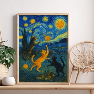 Op de afbeelding: Een ingelijste print met katten die spelen onder een sterrenhemel, in de stijl van Van Gogh. Het kunstwerk toont drie katten in oranje, zwart en bruin tegen een blauwgele achtergrond. De print zit in een houten lijst.