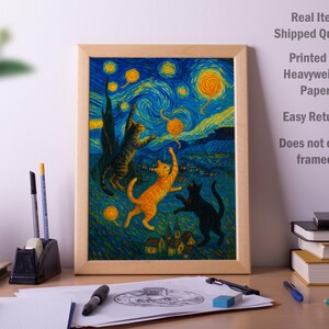 Op de afbeelding: Een ingelijste print met een grillige afbeelding van katten die onder een sterrenhemel spelen, die doet denken aan de stijl van Van Gogh. Het kunstwerk toont drie katten in tinten oranje, zwart en bruin, tegen een blauw-gele achtergrond.