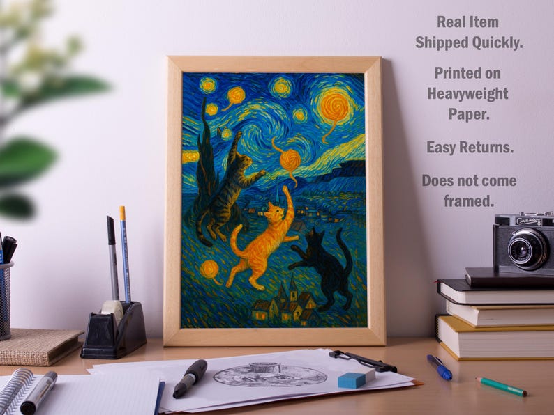 Op de afbeelding: Een ingelijste print met een grillige afbeelding van katten die onder een sterrenhemel spelen, die doet denken aan de stijl van Van Gogh. Het kunstwerk toont drie katten in tinten oranje, zwart en bruin, tegen een blauw-gele achtergrond.