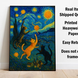 Op de afbeelding: Een ingelijste print van een grillig schilderij met drie katten die onder een sterrenhemel spelen. Het kunstwerk doet denken aan de stijl van Van Gogh, met wervelende blauwen, gelen en oranjes. De katten zijn afgebeeld in tinten oranje, bruin en zwart.
