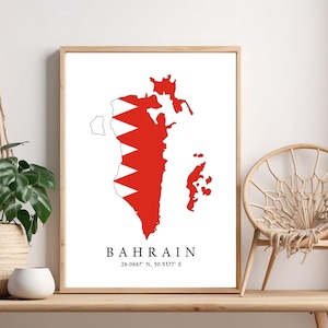 May include: A white framed print with a map of Bahrain in red and white, the colors of the Bahraini flag. The map is outlined in black and the text "BAHRAIN 26.0667° N, 50.5577° E" is printed below the map.