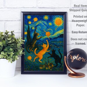 Op de afbeelding: Ingelijste kunstprint met een grillige sc&egrave;ne van katten die spelen onder een sterrenhemel, in de stijl van Van Gogh. Het kunstwerk toont drie katten in tinten oranje, bruin en zwart, tegen een levendige blauwe en gele achtergrond.