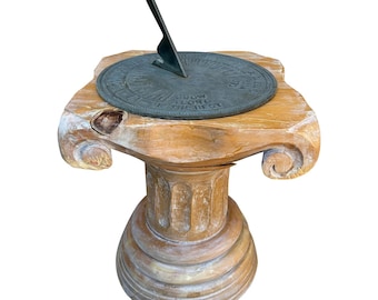 Reloj de sol de hierro patinado sobre pedestal neoclásico de madera tallada con columnas.