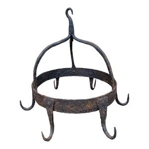 May include: A rustic, black metal pot rack with a circular base and multiple hooks. The rack is designed to hang pots and pans from the ceiling.