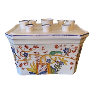 May include: White ceramic flower vase with a square base and eight small openings on top. The vase is decorated with a colorful floral and bird design.