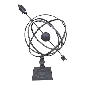 May include: A black metal armillary sphere with a compass needle pointing north. The sphere is on a square base.