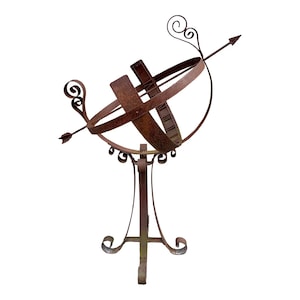 May include: A vintage, rusty metal sundial sculpture. The sundial features a spherical design with intersecting bands and an arrow pointing through the center. The base has a decorative, scrolled design. A unique piece for garden or home decor.