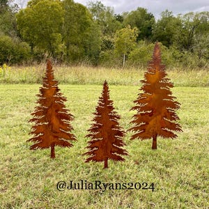 May include: Three rusty metal silhouette trees in a grassy field. The trees are in a row and are all the same size. The trees are a dark brown color and have a rough texture. The trees are in front of a green field and a cloudy sky.