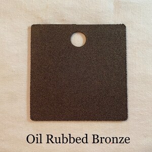 K&ouml;nnte beinhalten: Ein quadratisches Muster in &Ouml;l-Bronze-Finish. Das Muster hat ein Loch in der Mitte.