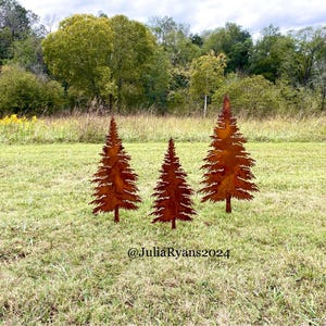 May include: Three rusty metal pine tree silhouettes stand on a grassy lawn. The trees are arranged in a row, with the tallest tree in the center. The trees are a popular outdoor decoration.