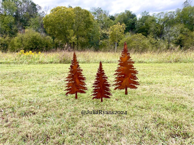 May include: Three rusty metal pine tree silhouettes stand on a grassy lawn. The trees are arranged in a row, with the tallest tree in the center. The trees are a popular outdoor decoration.