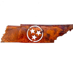 May include: A metal wall art piece shaped like the state of Tennessee, featuring a heavily rusted, textured brown finish. Centered on the map is a circular cutout containing three white stars arranged in a triangular formation.