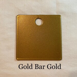 K&ouml;nnte beinhalten: Eine goldene Metallic-Farbmusterkarte mit einem runden Loch in der Mitte. Die Karte ist mit "Gold Bar Gold" beschriftet.