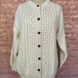 Cardigan Aron crème tricoté en pure laine vierge Highland Home Industries pour femmes des années 90, boutons en cuir marron. Taille moyenne.