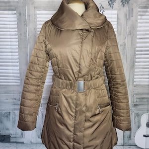 May include: A brown quilted jacket with a large collar, a belt with a buckle, and two zippered pockets.