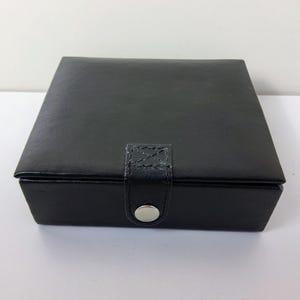 Vintage-Schmuckkästchen aus schwarzem Leder mit Druckknopfverschluss.