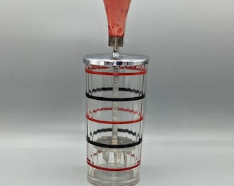 May include: Vintage glass cocktail mixer with a red and black striped design. The mixer has a red wooden handle and a chrome top. The glass cylinder is approximately 7 inches tall, with a metal agitator inside.