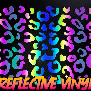 Può includere: Sfondo nero con un motivo di macchie di leopardo riflettenti multicolore in blu, verde, giallo e viola. Le parole "REFLECTIVE VINYL" sono scritte in arancione e rosa brillante nella parte inferiore.